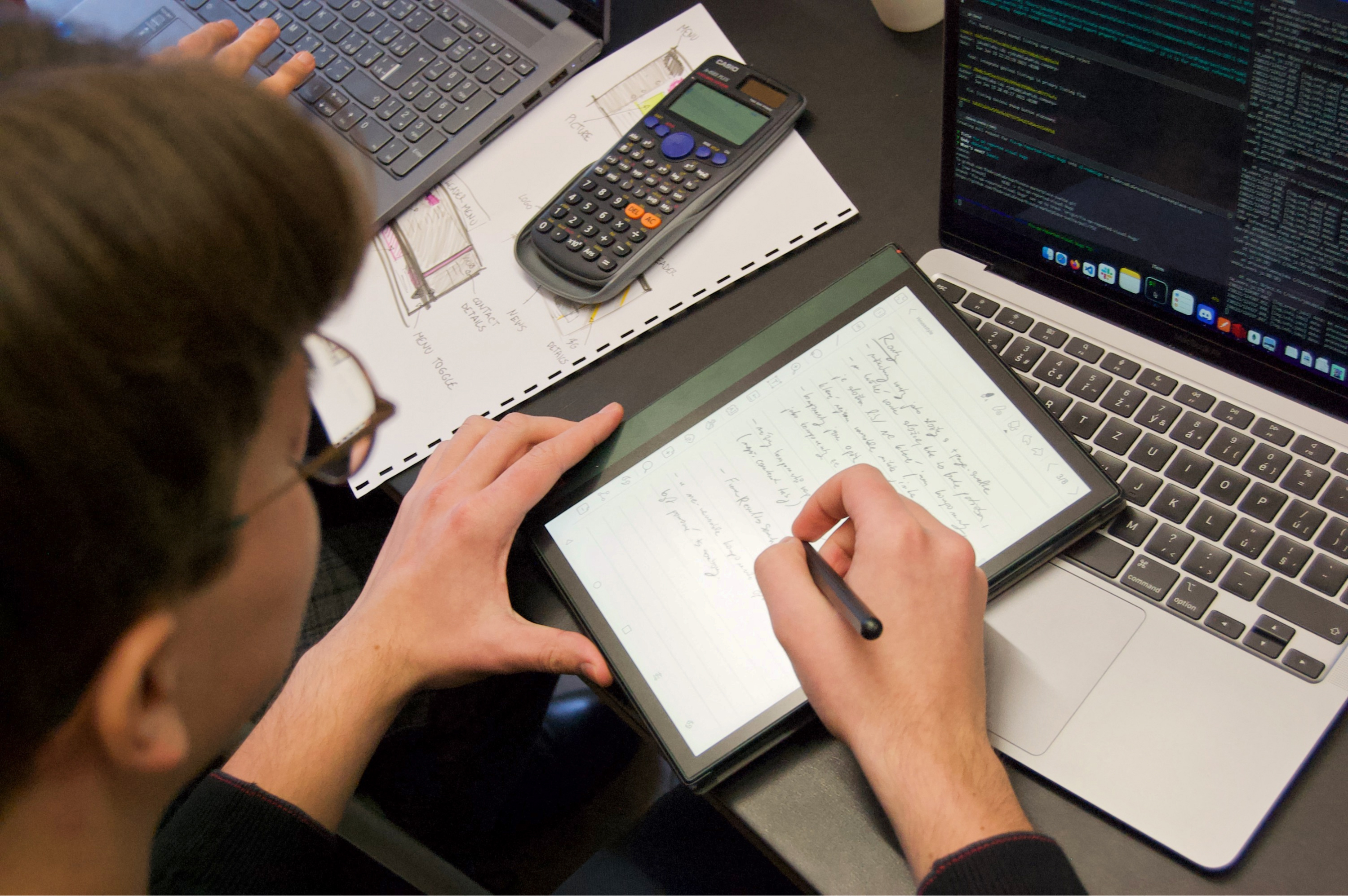 A young man writing on an e-book reader.